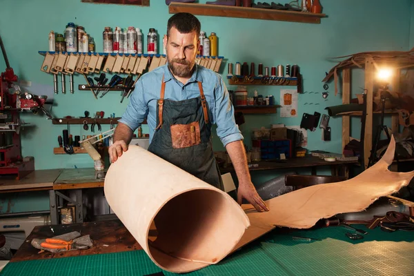 Artesano en delantal trabajando con cuero en taller — Foto de Stock