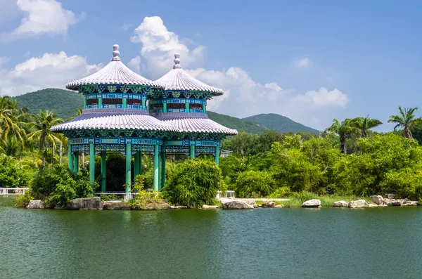 SANA, HAINAN, ÇİN - 10 Ekim 2019 'da Sanya Nanshan Kültür Merkezi' ndeki gölet kıyısında geleneksel Çin mimarisinin renkli bir geçidi, Sanya, Hainan, Çin