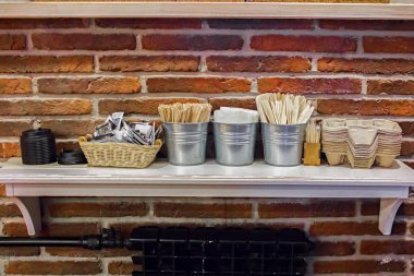 Çeşitli tek kullanımlık tahta çubuklar, tahta kaşık, diş macunları, bardak örtüleri, kutuları, peçeteleri ve şeker torbalarını kafenin ahşap tezgahına götür ve içkileri götür.