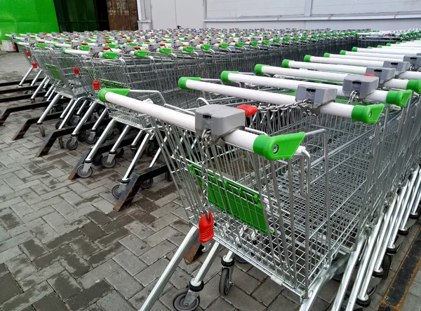 Rows of ready to use shopping carts lined-up in rows for storage near a supermarket or hyper market