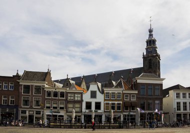 Gouda, Holland, Hollanda, Nisan 23, 2019. Gouda eski kentinde Pazar Meydanı, evler ve Sint-Janskerk kilise çan kulesi görünümü Hollandalı tarzı cepheler bir sokak (Hollanda 'da en yüksek)