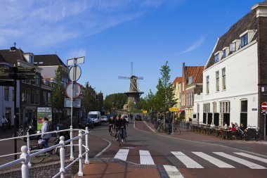 Leiden, Holland, Hollanda, Mayıs 22, 2019. Sokak manzarası, Molen de Valk Müzesi (Falcon yel değirmeni) geleneksel evler Park Bisiklet ve bicyclists 