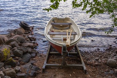 Finlandiya 'da göl kıyısında vinci olan bir kayıkta kırmızı bir kayık (kürek).