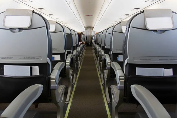 在飞机机舱里有一排座位和乘客的长廊 图库图片