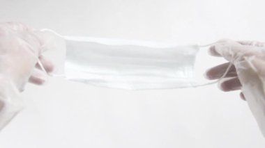 Ellerinde eldivenlerle kameraya yaklaşan mavi bir ilaç koruyucu maskesi. Manzarayı kapat. Antivirüs korumanın kutsallığı