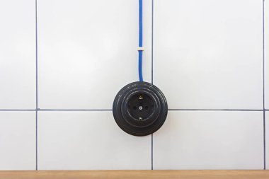  Beyaz seramik kiremitlerin arka planında eski siyah AB güç soketi