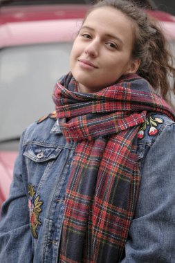 Güzel çekici kız bir şehir sokak arka plan üzerinde kırmızı kareli atkı ile