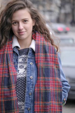 Güzel çekici kız bir şehir sokak arka plan üzerinde kırmızı kareli atkı ile