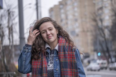 Güzel çekici kız bir şehir sokak arka plan üzerinde kırmızı kareli atkı ile