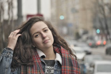 Güzel çekici kız bir şehir sokak arka plan üzerinde kırmızı kareli atkı ile