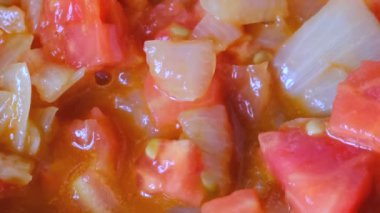 Beyaz soğan olmayan bir sopa teflon ızgara üzerinde zeytinyağı ile kırmızı taze domates ile haşlanmış küçük parçalar halinde doğranmış, video klip yakın çekim zoom ve kamera hareketi kullanarak çekim