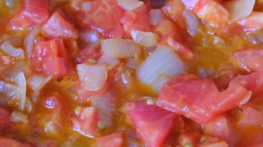 Beyaz soğan olmayan bir sopa teflon ızgara üzerinde zeytinyağı ile kırmızı taze domates ile haşlanmış küçük parçalar halinde doğranmış, video klip yakın çekim zoom ve kamera hareketi kullanarak çekim