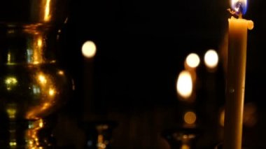 İnce kilise mumları karanlık yakın çekimde kutsal görüntülerin yakınında bir Ortodoks Hıristiyan kilisesinde yakmak, yakınlaştırma ve kamera hareketli kullanılarak filme