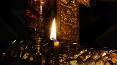 İnce kilise mumları karanlık yakın çekimde kutsal görüntülerin yakınında bir Ortodoks Hıristiyan kilisesinde yakmak, yakınlaştırma ve kamera hareketli kullanılarak filme