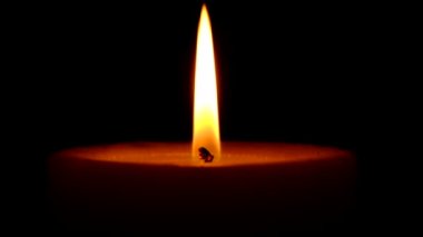 Büyük bir kalın mum yanar sonra rüzgar onu söndürür, siyah arka plan yakın çekim yavaş hareket