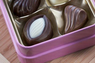 Beyaz ve koyu sütlü çikolatalardan oluşan çeşitli tatlıların yemek arkaplan fotoğrafı küçük bir kutuda bir masanın üzerinde yatıyor.