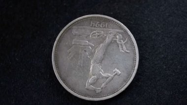 1924 tarihli 50 kopeklik gümüş bir Sovyet sikkesinin tersi siyah bir arkaplan üzerinde kameranın önünde yavaşça dönüyor.