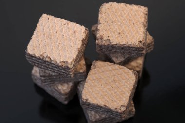 Küçük kare tatlı waffle parçaları ile çikolata dolgulu siyah arka plan yakın çekim makro fotoğraf