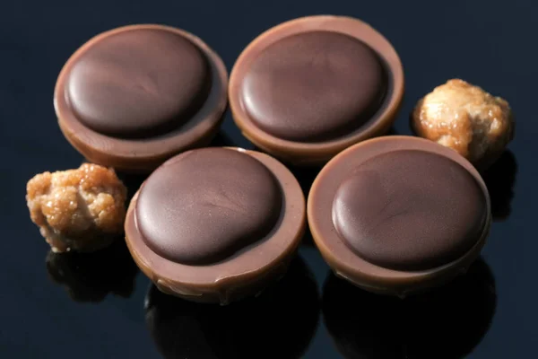 在黑镜背景巨幅照片上加入坚果的巧克力糖果 — 图库照片