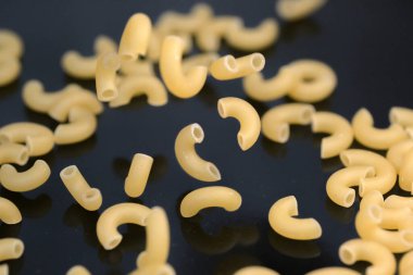 Premium buğday unundan yapılan küçük makarna ve yumurtalar karanlık bir masa yüzeyine yakın plan market arka plan makro fotoğrafçılığına düşer.