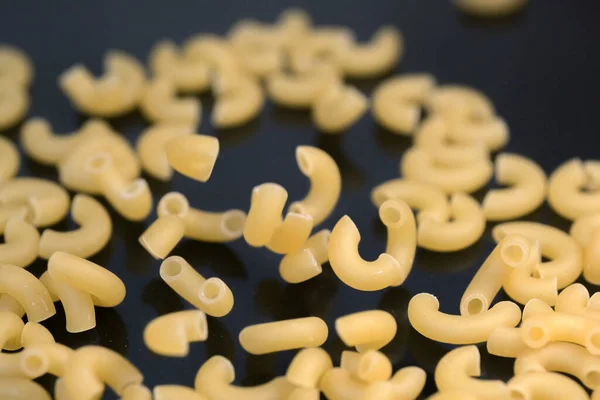 Small pasta made from premium wheat flour and eggs fall on a dark table surface close-up grocery background macro photography