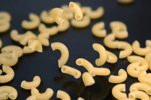 Small pasta made from premium wheat flour and eggs fall on a dark table surface close-up grocery background macro photography