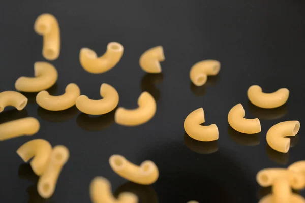 Small pasta made from premium wheat flour and eggs fall on a dark table surface close-up grocery background macro photography