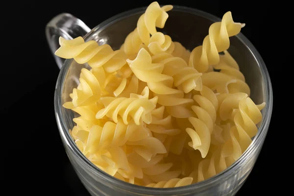 Small pasta made from premium wheat flour and eggs fall on a dark table surface close-up grocery background macro photography