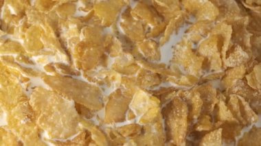 Kremalı ve kremalı mısır gevrekleri yakın plan bir tabakta kamera makro video çekiminin önünde döner.