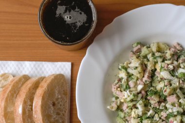 Sosisli sebze salatası, haşlanmış yumurta ve patates, salatalık, turp, maydanoz ve dereotlu. Ekmek kvass ve ekşi krema ile soğuk bir ilk yemek olarak kullanılır..