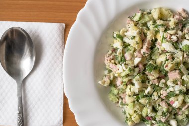 Sosisli sebze salatası, haşlanmış yumurta ve patates, salatalık, turp, maydanoz ve dereotlu. Ekmek kvass ve ekşi krema ile soğuk bir ilk yemek olarak kullanılır..