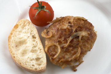 Lezzetli taze et, sığır eti, domuz eti ve soğan karışımı bir dilim beyaz ekmek ve beyaz bir tabak makro fotoğrafta domatesle yakın plan soğan kızartması.