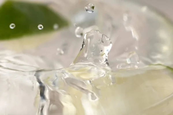 Refreshing lemonade with slices of lime with ice in a transparent sweaty glass cup close-up macro photo