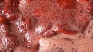 Çilek reçelini kendi suyunda yapma süreci. Gaz sobası makro video çekiminde açık bir kaseye şeker eklenmesi.