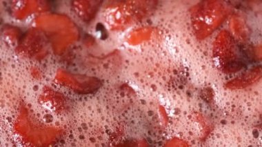 Çilek reçelini kendi suyunda yapma süreci. Gaz sobası makro video çekiminde açık bir kaseye şeker eklenmesi.
