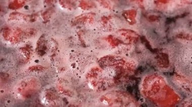 Çilek reçelini kendi suyunda yapma süreci. Gaz sobası makro video çekiminde açık bir kaseye şeker eklenmesi.