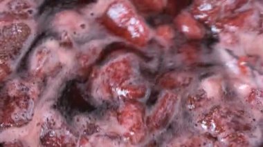 Çilek reçelini kendi suyunda yapma süreci. Gaz sobası makro video çekiminde açık bir kaseye şeker eklenmesi.