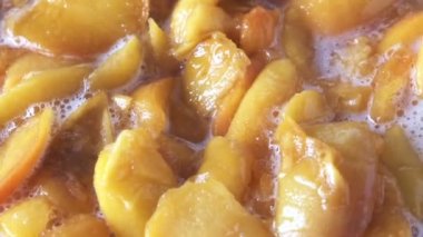 Evde şeftali reçeli pişiriyorum meyve suyu şurubunda açık bir tavada yakın çekim makro çekim gıda taşınıyor.