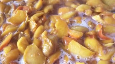 Evde şeftali reçeli pişiriyorum meyve suyu şurubunda açık bir tavada yakın çekim makro çekim gıda taşınıyor.