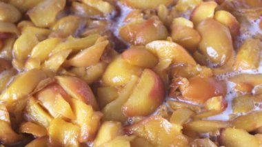 Evde şeftali reçeli pişiriyorum meyve suyu şurubunda açık bir tavada yakın çekim makro çekim gıda taşınıyor.
