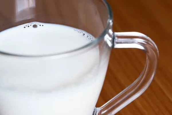 キッチンテーブルの上のミルクのガラス透過マグカップ クローズアップ マクロ写真 — ストック写真