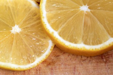 Yuvarlak limon dilimleri kesme tahtasının üzerinde yer alır. Yakın çekim makro fotoğraf, vejetaryen arka plan.