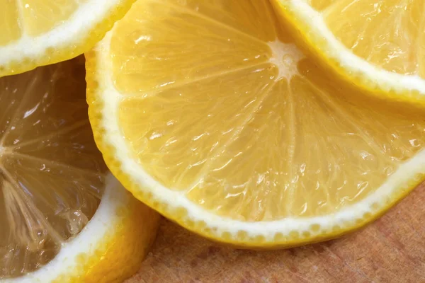 Yuvarlak limon dilimleri kesme tahtasının üzerinde yer alır. Yakın çekim makro fotoğraf, vejetaryen arka plan.