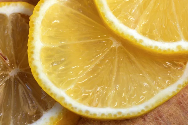 Yuvarlak limon dilimleri kesme tahtasının üzerinde yer alır. Yakın çekim makro fotoğraf, vejetaryen arka plan.