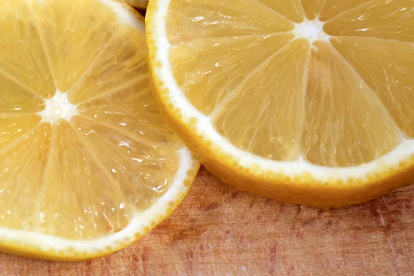 Yuvarlak limon dilimleri kesme tahtasının üzerinde yer alır. Yakın çekim makro fotoğraf, vejetaryen arka plan.