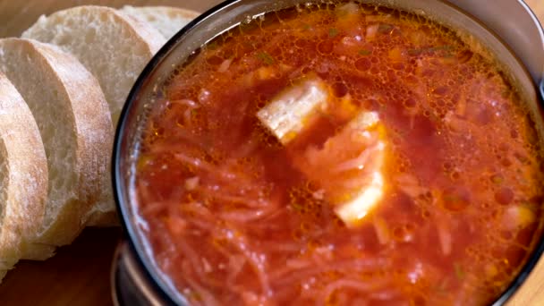 A plate of the first course of borscht soup with tomatoes, cabbage and potatoes in meat broth stands on the dining table, close-up, macro video — Stock Footage Plate First Course Borscht Soup Tomatoes Cabbage Potatoes Meat Broth Video Clip