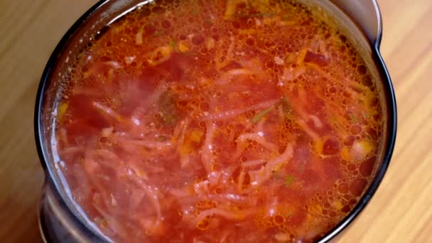 A plate of the first course of borscht soup with tomatoes, cabbage and potatoes in meat broth stands on the dining table, close-up, macro video — Stock Footage Plate First Course Borscht Soup Tomatoes Cabbage Potatoes Meat Broth Royalty Free Stock Footage