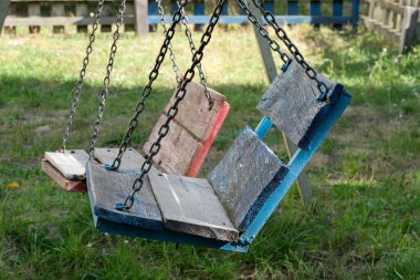 Tahta salıncaklar zincirlerden nazikçe sarkıyor, güneşli bahçede eğlenceli maceralara hazır..