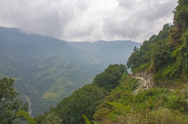 Turistler Nepal Himalayaları 'nın dağları arasında izleri takip ediyorlar.