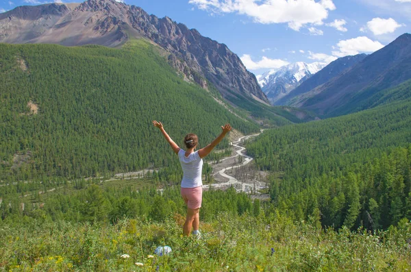 Landscape girl in the mountains looks away with raised hands